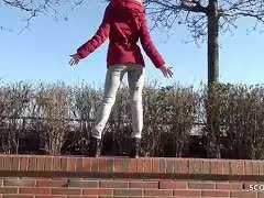 Schlankes Girl im roten Wintermantel mit Pelzkragen beißt schüchtern auf den Finger