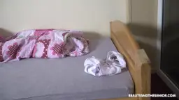 Älterer grauhaariger Mann sitzt entspannt mit runtergelassener Hose auf dem Bett und hält eine silberne Flasche