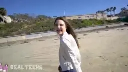 Megan lacht am Sandstrand, offenes weißes Hemd, blauer Himmel